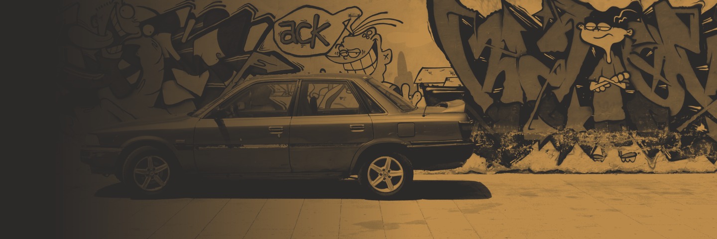 A car parked in front of a graffiti-covered wall on a Cape Town street.